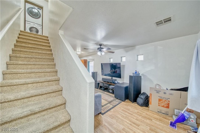 stairway with wood finished floors, visible vents, stacked washer / drying machine, and ceiling fan