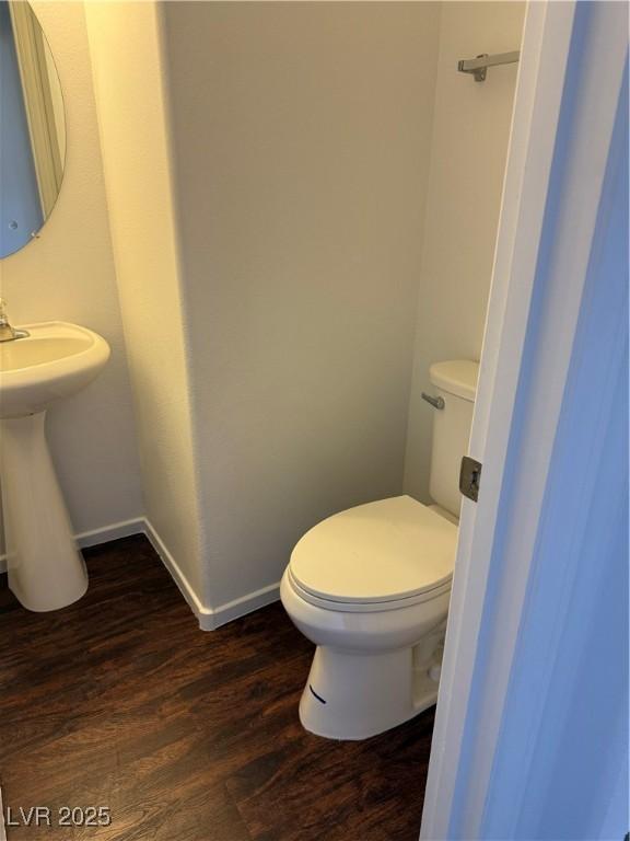 bathroom featuring a sink, wood finished floors, toilet, and baseboards