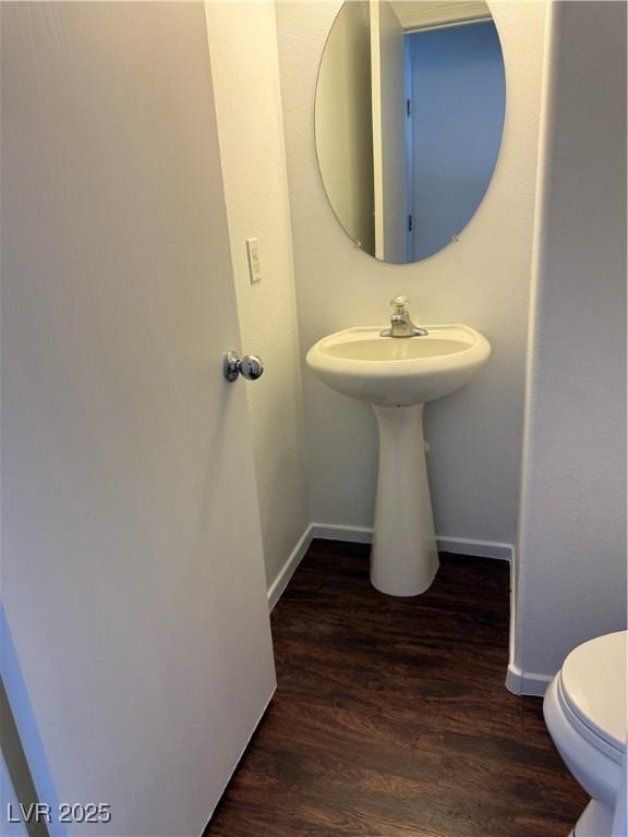 half bathroom with toilet, baseboards, and wood finished floors