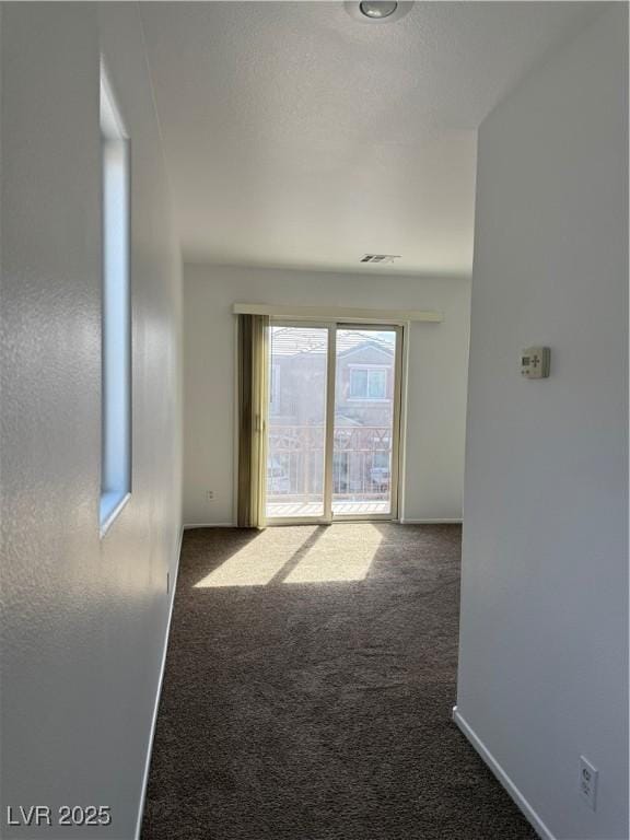 carpeted spare room with visible vents, baseboards, and a textured ceiling