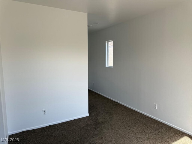 unfurnished room with baseboards and dark carpet