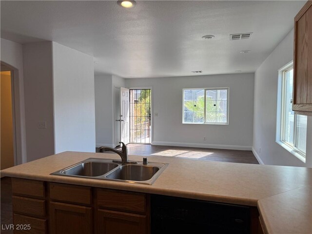 kitchen featuring visible vents, open floor plan, a sink, and light countertops