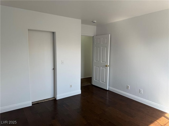 unfurnished bedroom with dark wood-style flooring and baseboards