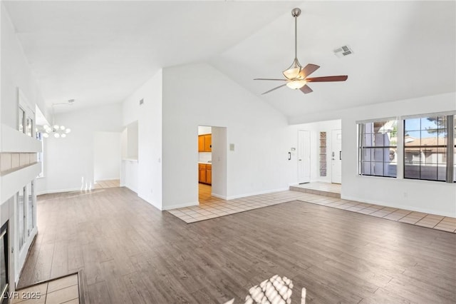 unfurnished living room featuring ceiling fan with notable chandelier, high vaulted ceiling, visible vents, and light wood-style floors