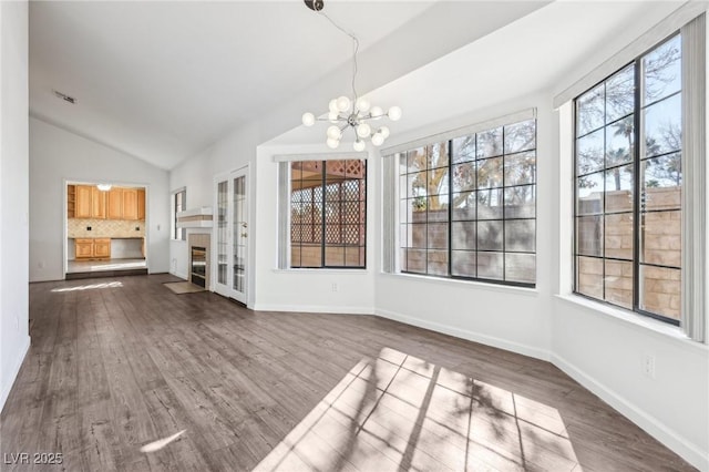 unfurnished dining area with lofted ceiling, dark wood-type flooring, baseboards, and an inviting chandelier