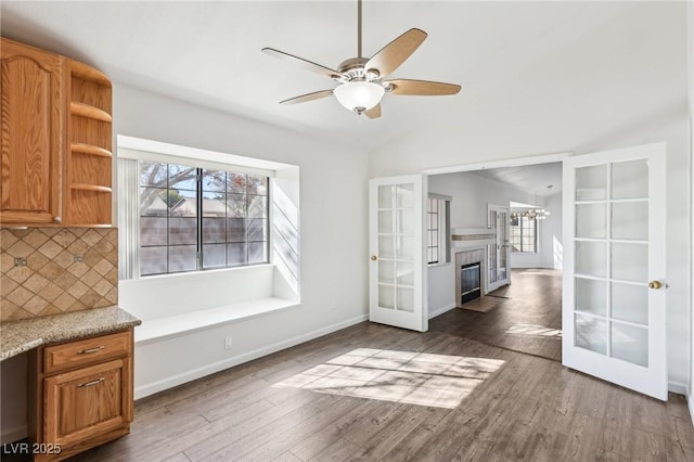 unfurnished dining area with ceiling fan, french doors, wood finished floors, and baseboards