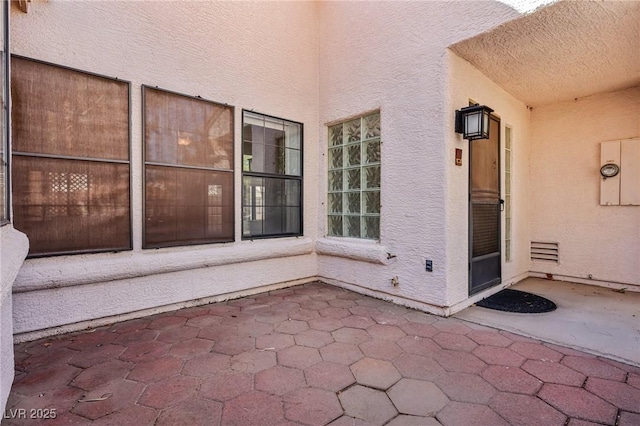 entrance to property with a patio and stucco siding