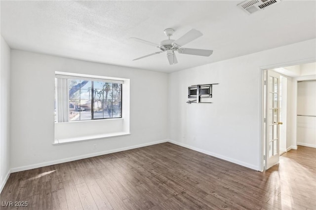 unfurnished room featuring a ceiling fan, wood-type flooring, visible vents, and baseboards