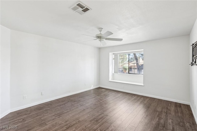 unfurnished room with dark wood-style floors, baseboards, visible vents, and a ceiling fan