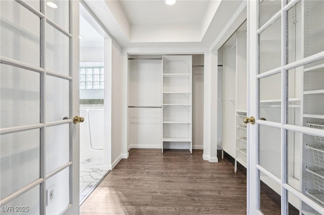 walk in closet with french doors and wood finished floors