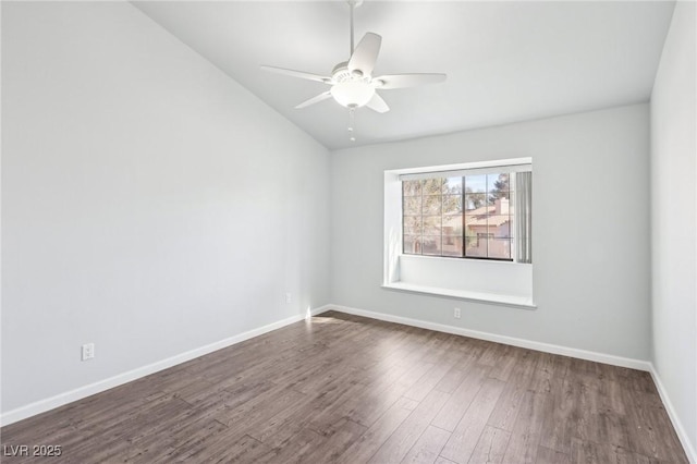 empty room with vaulted ceiling, dark wood-style flooring, a ceiling fan, and baseboards