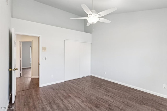 unfurnished bedroom featuring dark wood-type flooring, a closet, high vaulted ceiling, and baseboards