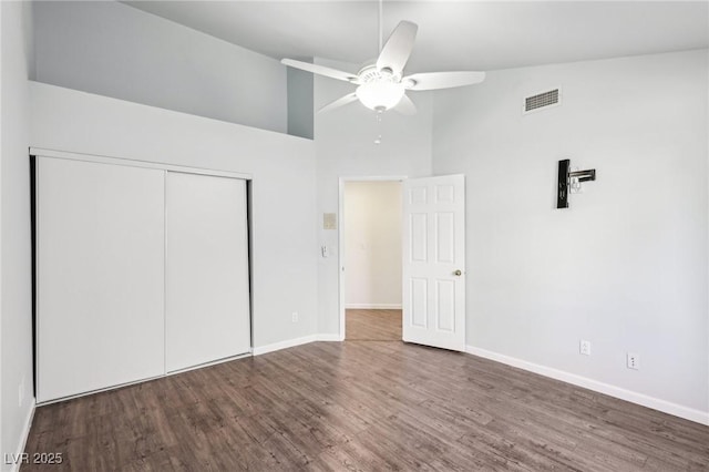 unfurnished bedroom featuring visible vents, baseboards, a ceiling fan, wood finished floors, and a closet