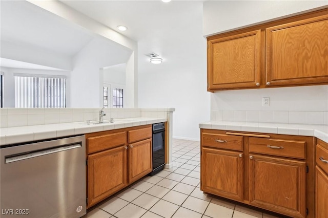 kitchen with light tile patterned floors, visible vents, stainless steel dishwasher, brown cabinetry, and a sink