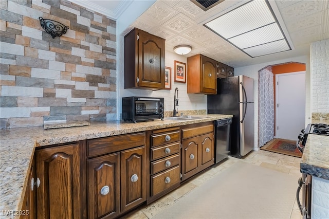 kitchen with black dishwasher, a toaster, tasteful backsplash, stone finish flooring, and a sink