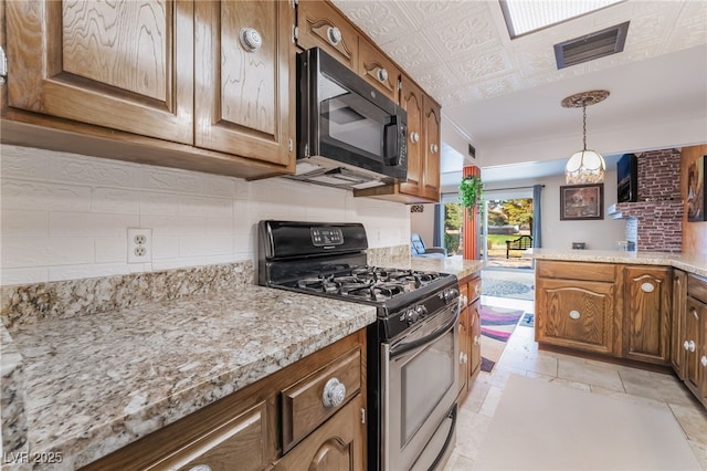 kitchen with gas stove, black microwave, and brown cabinets