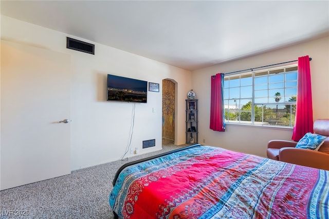 carpeted bedroom with arched walkways and visible vents