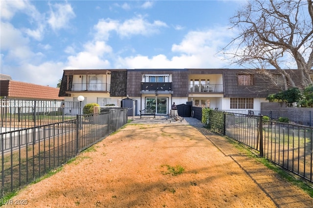 townhome / multi-family property featuring a balcony, fence private yard, and mansard roof