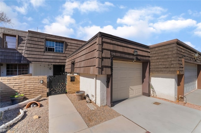 multi unit property with a garage, concrete driveway, stucco siding, and mansard roof