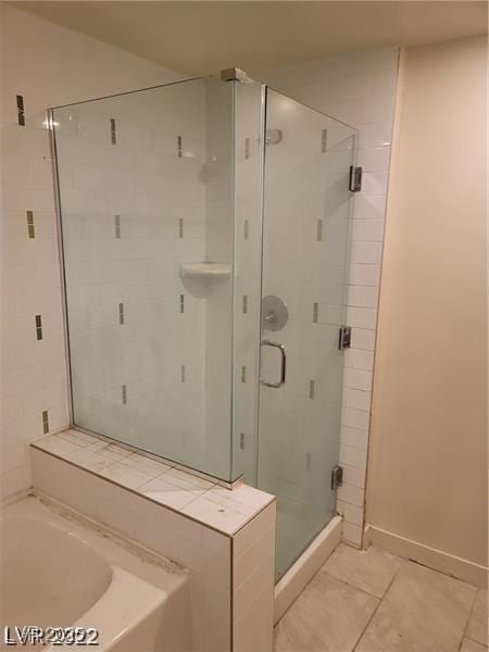 bathroom featuring a stall shower, baseboards, a bath, and tile patterned floors