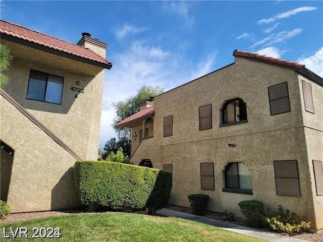 view of side of property featuring a tile roof, a chimney, and stucco siding