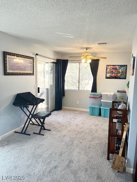 interior space with visible vents, a ceiling fan, carpet flooring, a textured ceiling, and baseboards