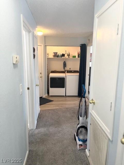 hall with washing machine and dryer, baseboards, a textured ceiling, and light colored carpet