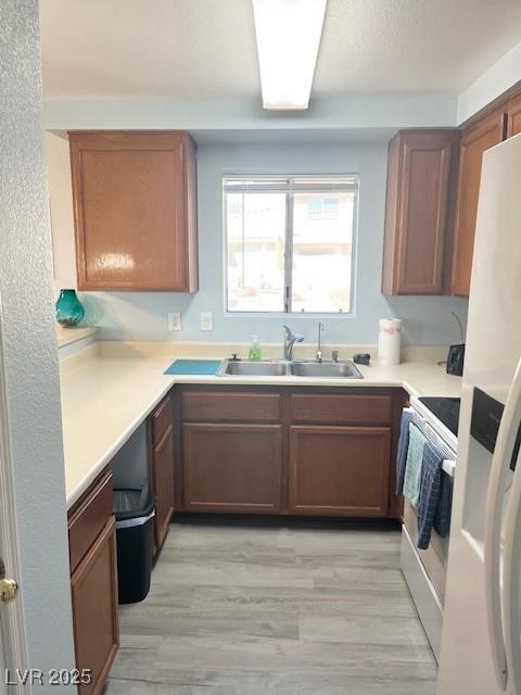 kitchen featuring white appliances, light countertops, a sink, and light wood-style flooring