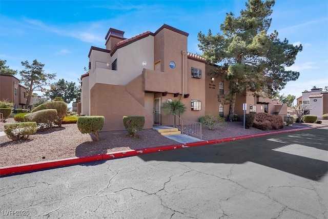 view of side of property featuring a tiled roof, a residential view, and stucco siding