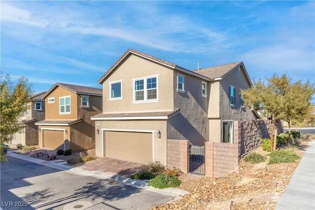 view of front of home featuring a gate, fence, an attached garage, stucco siding, and decorative driveway