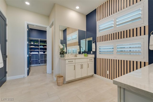 full bathroom featuring a walk in closet, recessed lighting, vanity, baseboards, and wallpapered walls