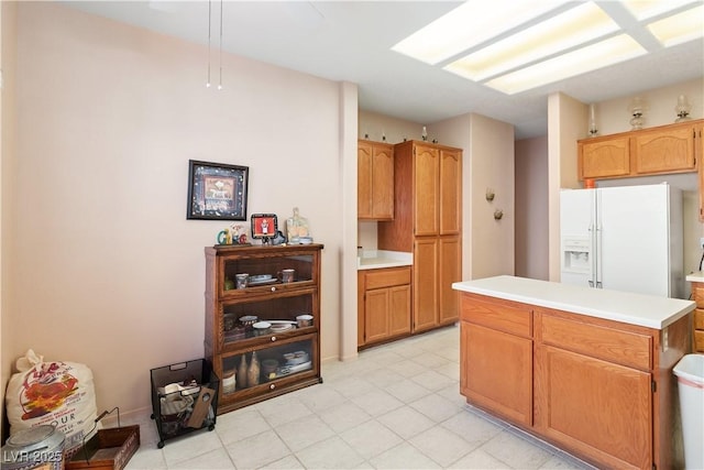 kitchen featuring light countertops, white refrigerator with ice dispenser, and brown cabinets