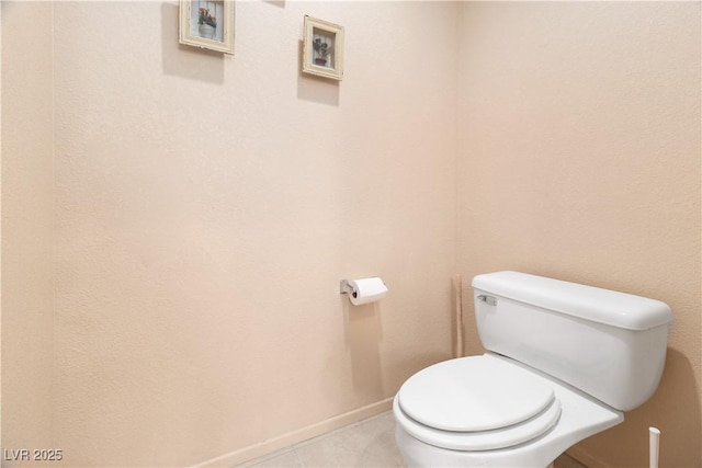 bathroom with toilet, tile patterned flooring, and baseboards