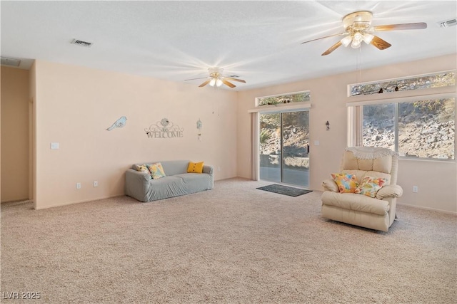 living area with carpet, visible vents, and a ceiling fan