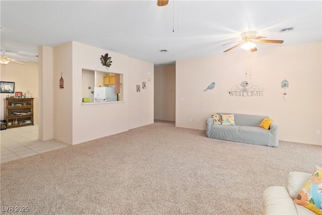 living room featuring visible vents, a ceiling fan, and light colored carpet