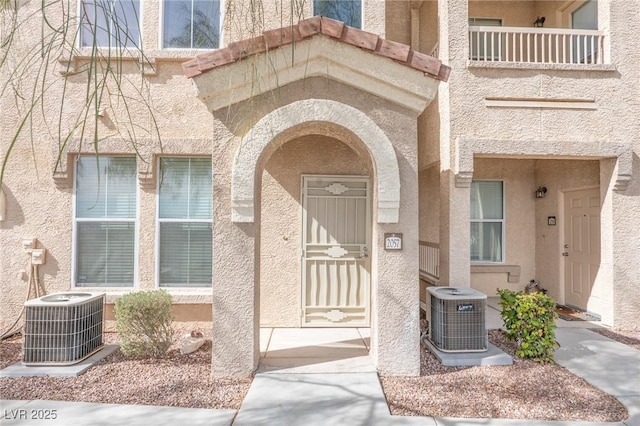 doorway to property featuring cooling unit and stucco siding