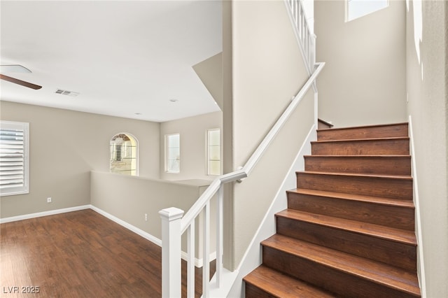 staircase with ceiling fan, wood finished floors, visible vents, and baseboards