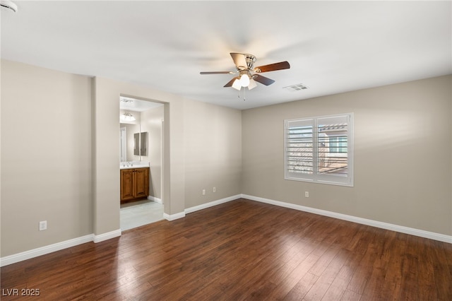 spare room with ceiling fan, visible vents, baseboards, and dark wood-type flooring