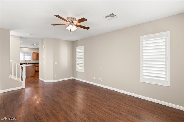 unfurnished room featuring baseboards, visible vents, dark wood finished floors, ceiling fan, and a sink