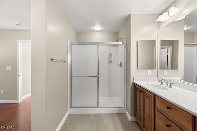 full bathroom featuring a stall shower, vanity, and baseboards