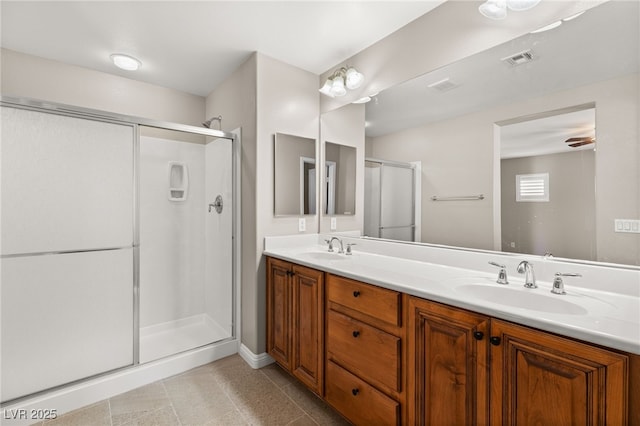 bathroom with double vanity, a stall shower, visible vents, and a sink