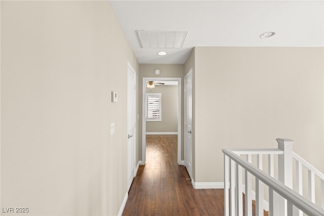 corridor with baseboards, visible vents, dark wood-style flooring, and an upstairs landing