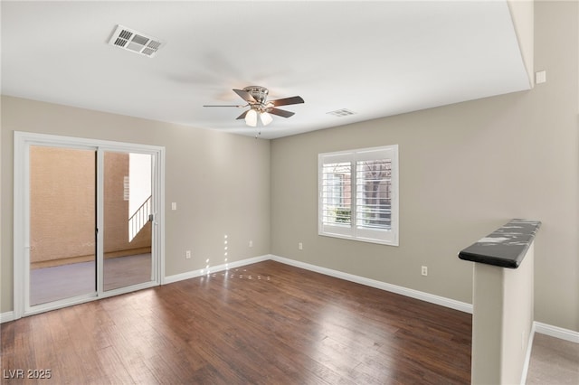 empty room with baseboards, visible vents, and dark wood-style flooring