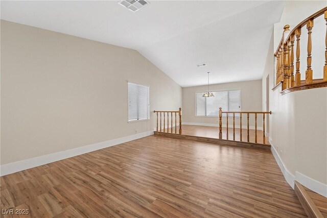 empty room featuring vaulted ceiling, wood finished floors, visible vents, and baseboards