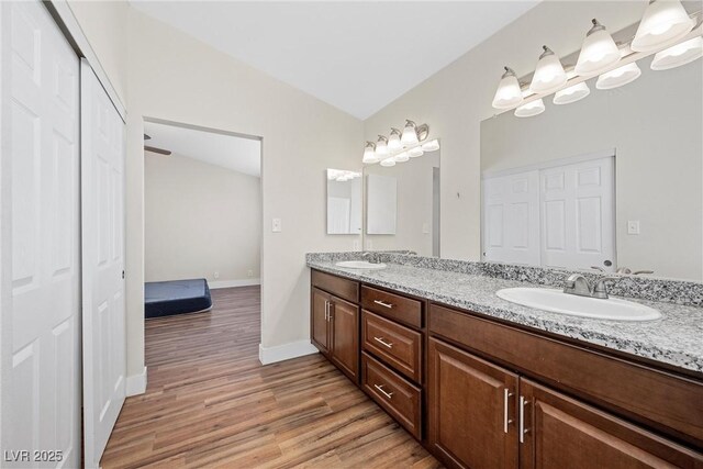 full bathroom featuring double vanity, a sink, baseboards, and wood finished floors