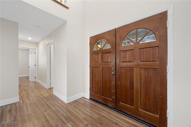 foyer entrance with light wood-style floors and baseboards