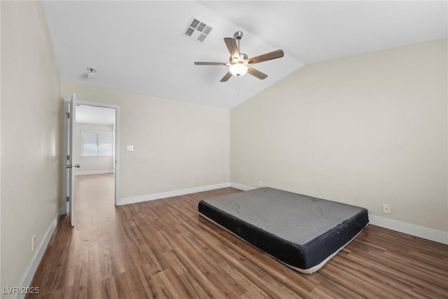 unfurnished bedroom with visible vents, ceiling fan, vaulted ceiling, wood finished floors, and baseboards