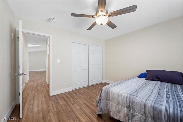 bedroom with a closet, wood finished floors, a ceiling fan, and baseboards