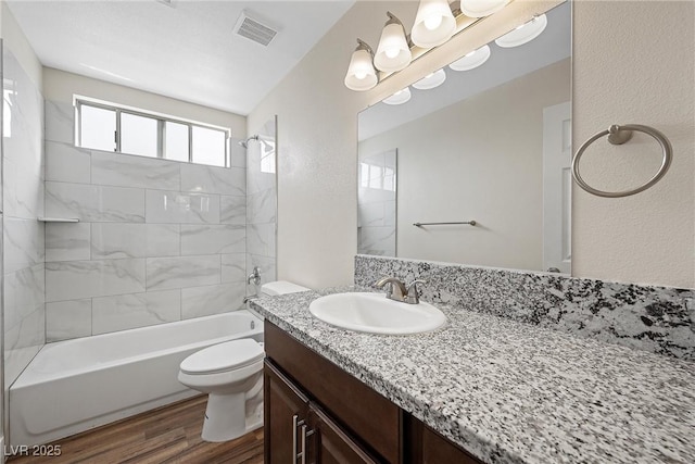 full bathroom with toilet, wood finished floors, vanity, visible vents, and  shower combination