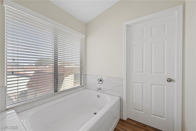 full bathroom with plenty of natural light, wood finished floors, and a bath